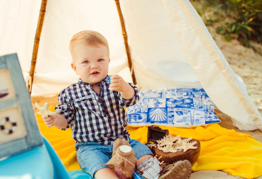 toddler boy sitting on blanket under tent