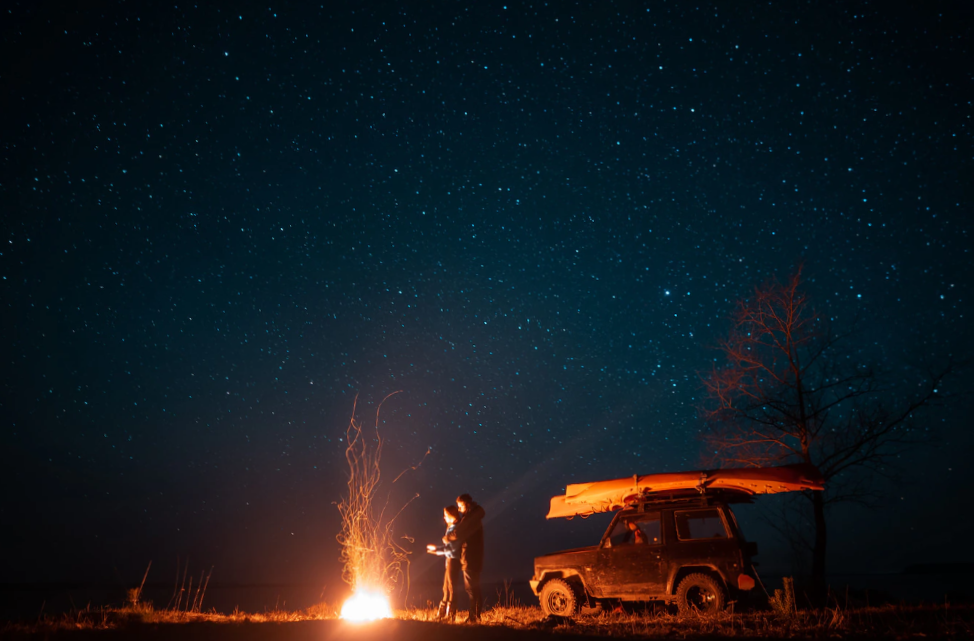 Happy couple man and woman standing in front burning bonfire