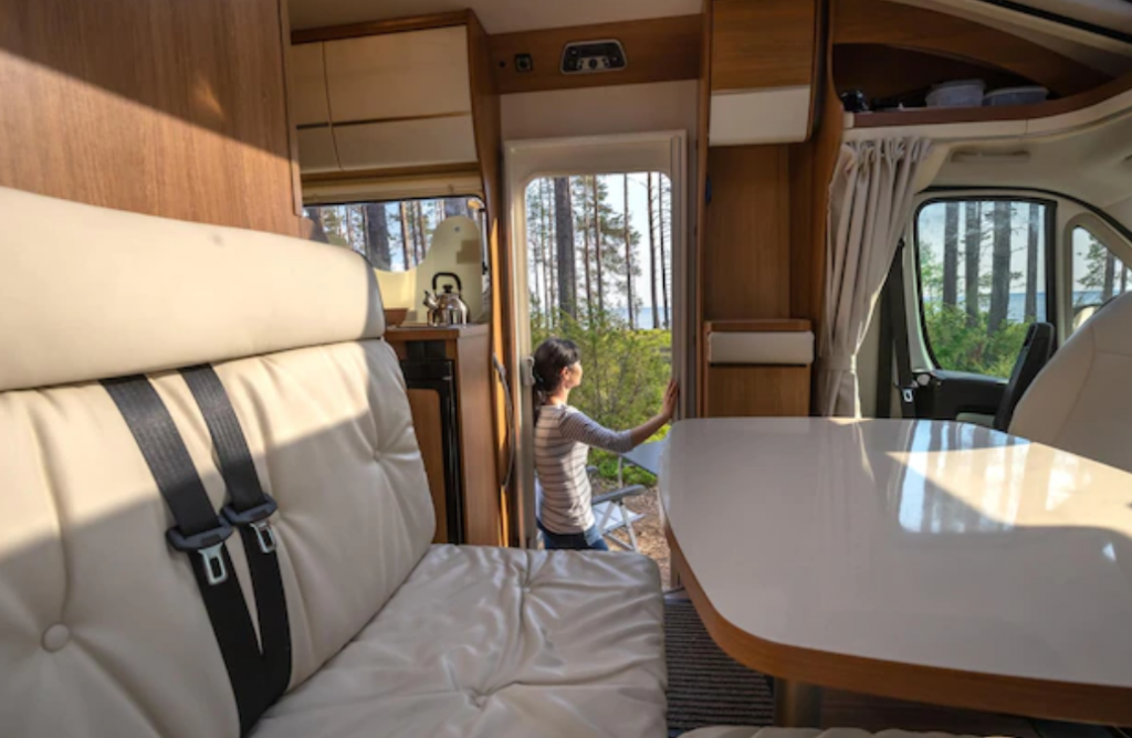 Woman in the interior of a camper rv motorhome with a cup of coffee looking at nature.